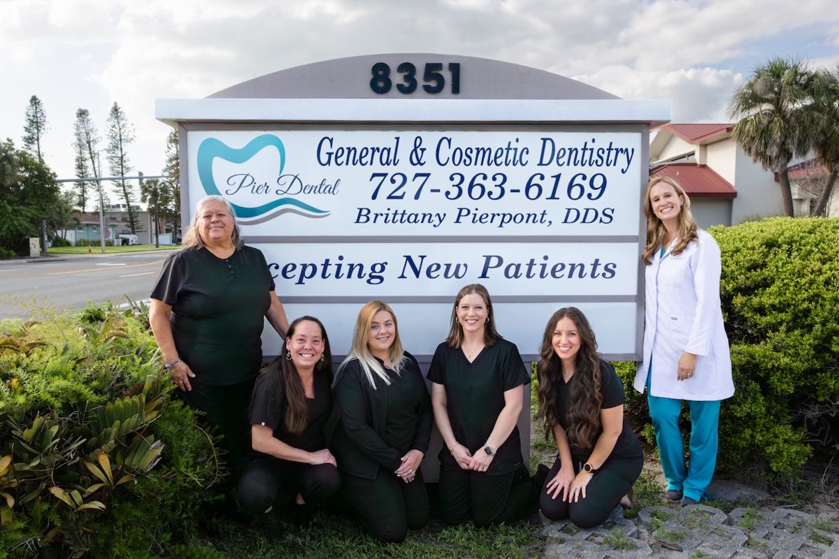 The Pier Dental team in front of the office sign at 8351 Blind Pass Rd, dentist in Dunedin Isles, FL